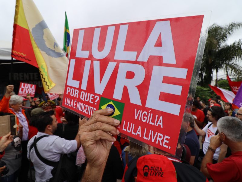 A man holds a sign in front of the Curitiba federal prison where former president Luiz Inacio Lula da Silva is behind held. The sign reads: “Free Lula. Why? Because he's innocent.”