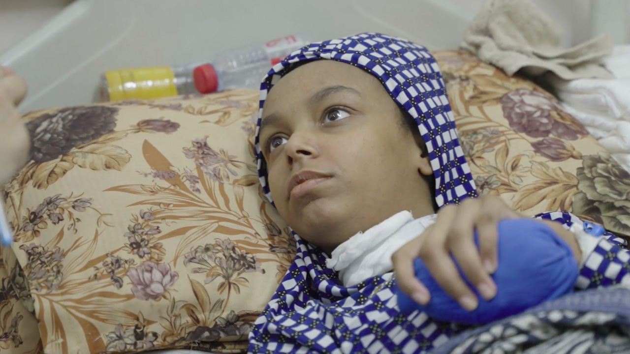 A child in Gaza with a head wound receives care in Al-Aqsa Martyrs' Hospital in Deir al-Balah. Still from video by