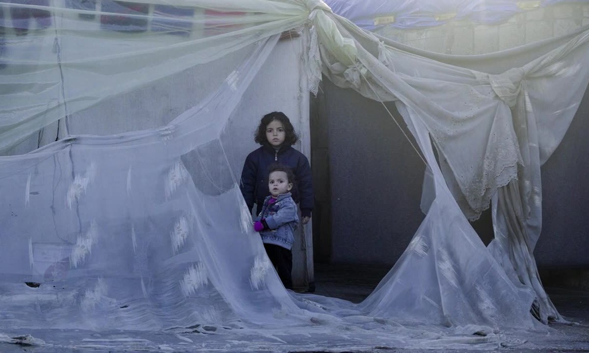 Two girls gaze out from a tent in Gaza.