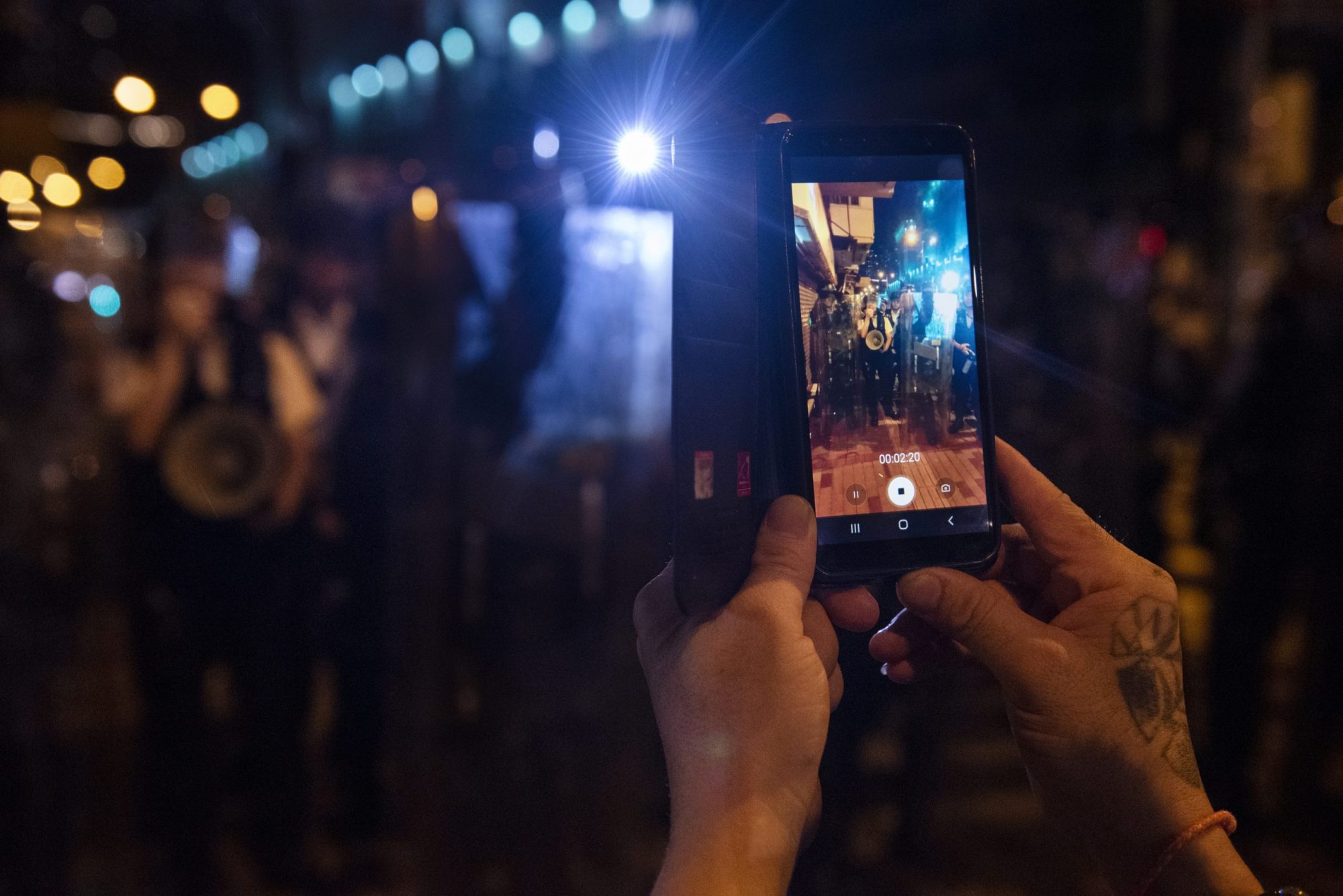 A protester records the riot police's action with his mobile phone during the demonstration. Thousands of protesters surrounded the Sham Shui Po district police station to demand the release of the student union president Keith Fong Chung Yin who was arrested for buying a torch-like laser pointer which the police consider it as weapons, sparking the latest confrontation between the protesters and the police. Photo by Miguel Candela/SOPA Images/LightRocket via Getty Images