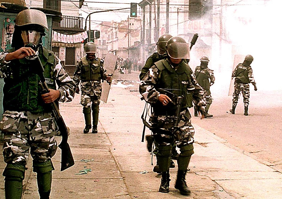 Riot police are positioned on a tear gas-enshrouded street during a protest by an estimated 2,000 residents against a sharp hike in water prices February 2000 in Cochabamba, Bolivia's second largest city.