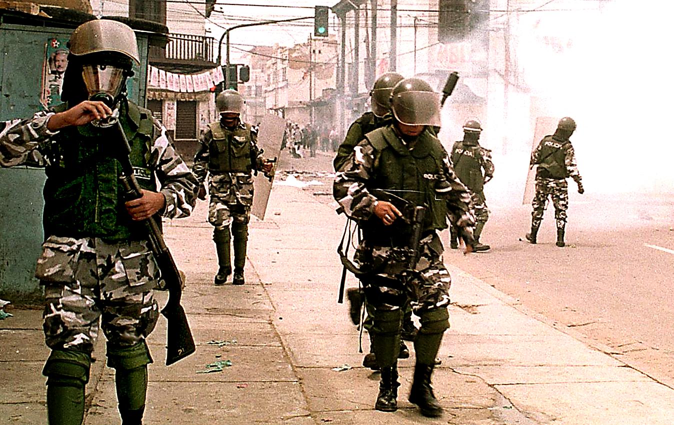 Riot police are positioned on a tear gas-enshrouded street during a protest by an estimated 2,000 residents against a sharp hike in water prices February 2000 in Cochabamba, Bolivia's second largest city.