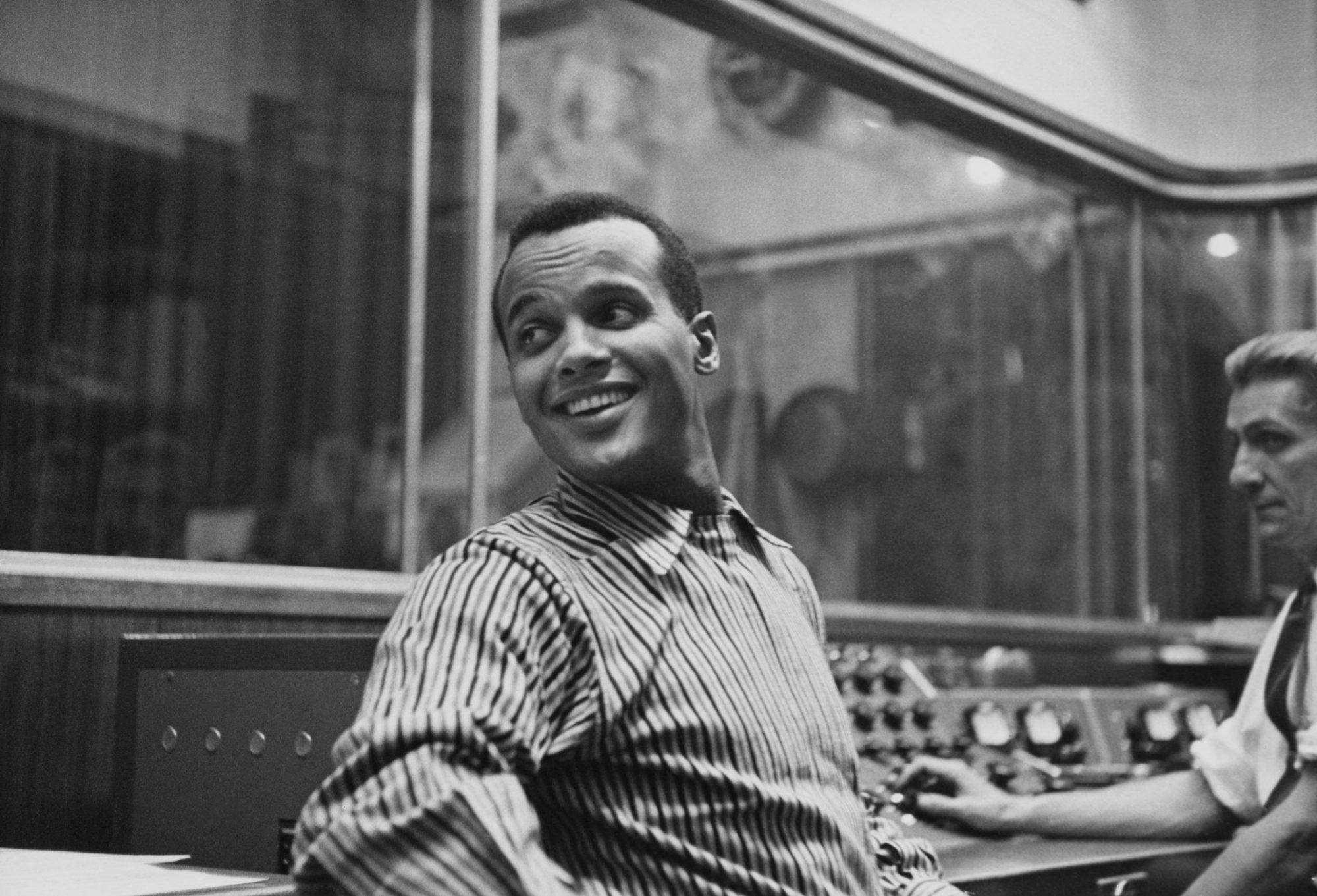 American singer-songwriter and civil rights activist Harry Belafonte, wearing a striped shirt, in an recording studio, circa 1957. Photo by Archive Photos/Hulton Archive/Getty Images.
