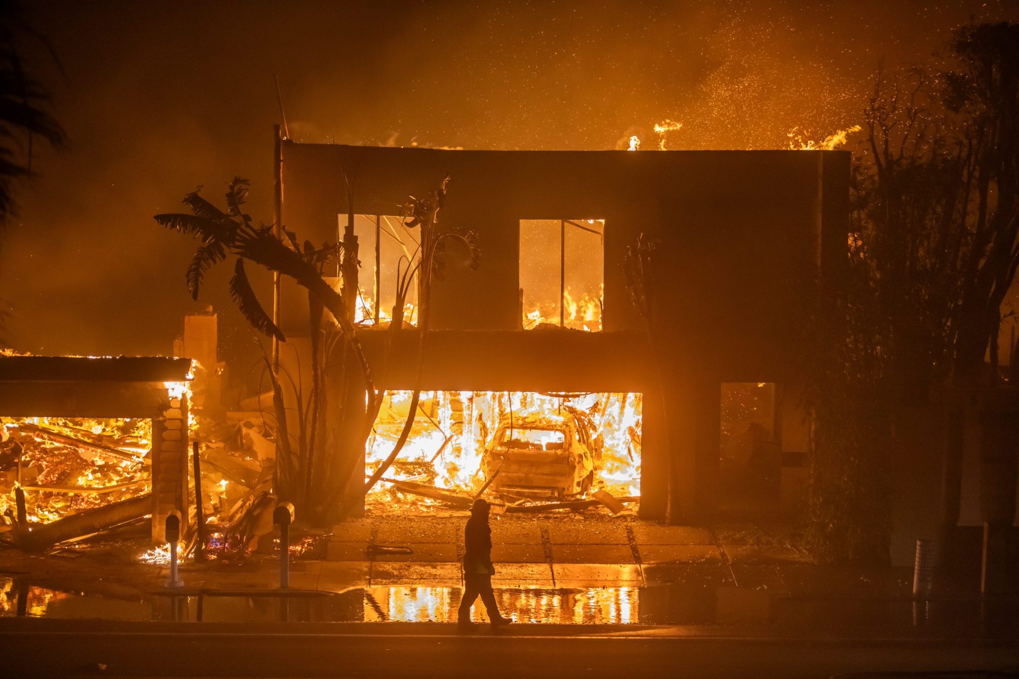 A firefighter watches the flames from the Palisades Fire burning homes on the Pacific Coast Highway amid a powerful windstorm on January 8, 2025 in Los Angeles, California. Photo by Apu Gomes/Getty Images