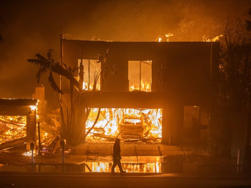 A firefighter watches the flames from the Palisades Fire burning homes on the Pacific Coast Highway amid a powerful windstorm on January 8, 2025 in Los Angeles, California. Photo by Apu Gomes/Getty Images