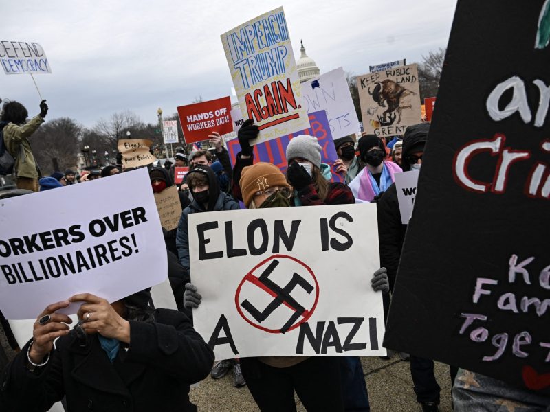 People hold up signs as they protest against US President Donald Trump and Elon Musk's "Department of Government Efficiency" (DOGE) outside of the US Department of Labor near the US Capitol in Washington, DC, February 5, 2025. Photo by DREW ANGERER/AFP via Getty Images