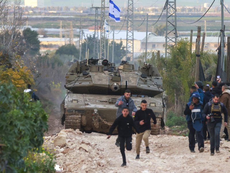 Palestinian children and journalists disperse as Israeli tanks enter the Jenin camp for Palestinian refugees in the occupied West Bank, on February 23, 2025. Photo by JAAFAR ASHTIYEH/AFP via Getty Images