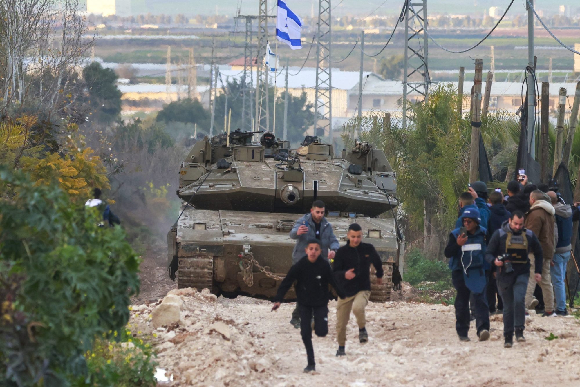 Palestinian children and journalists disperse as Israeli tanks enter the Jenin camp for Palestinian refugees in the occupied West Bank, on February 23, 2025. Photo by JAAFAR ASHTIYEH/AFP via Getty Images