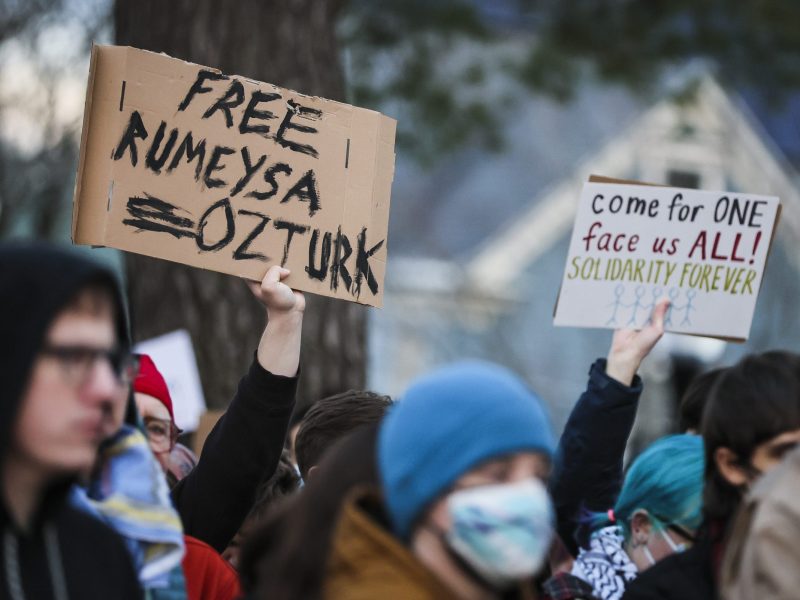 Protesters hold signs reading "Free Rumeysa Ozturk" and "come for one face us all! solidarity forever" during a demonstration at Powder House Park. Photo by Erin Clark/The Boston Globe via Getty Images