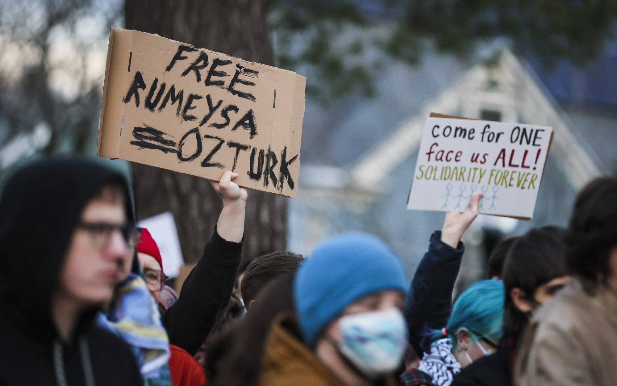 Protesters hold signs reading "Free Rumeysa Ozturk" and "come for one face us all! solidarity forever" during a demonstration at Powder House Park. Photo by Erin Clark/The Boston Globe via Getty Images