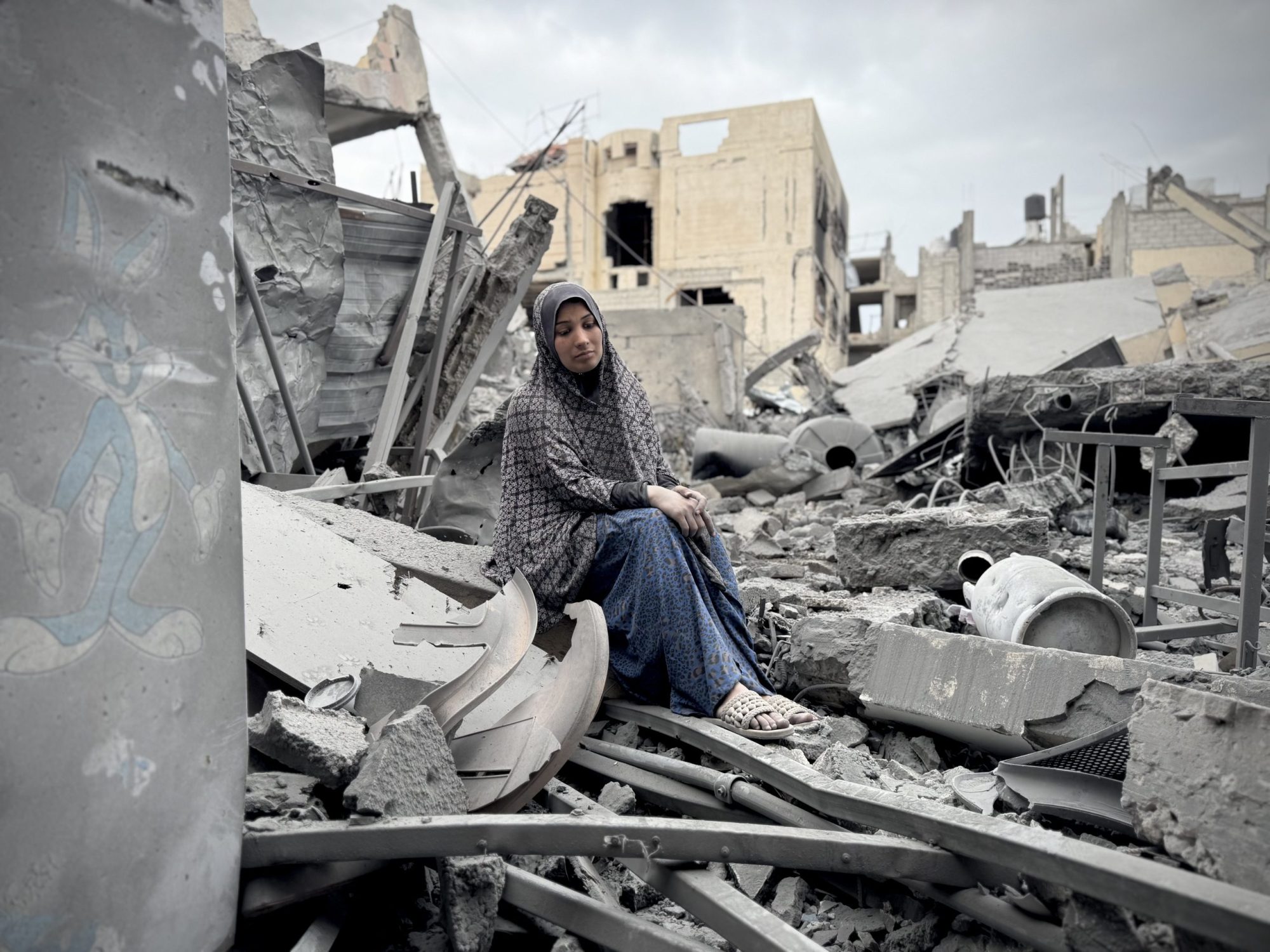 KHAN YUNIS, GAZA - APRIL 01: A woman is seen sitting among the rubble as Palestinians inspect a building destroyed in an Israeli army attack on a settlement on the third day of Eid al-Fitr in Khan Yunis, Gaza on April 01, 2025. Palestinian journalist Mohammed Saleh al-Bardawil, his wife and children lost their lives in the attack. Photo by Abdallah F.s. Alattar/Anadolu via Getty Images