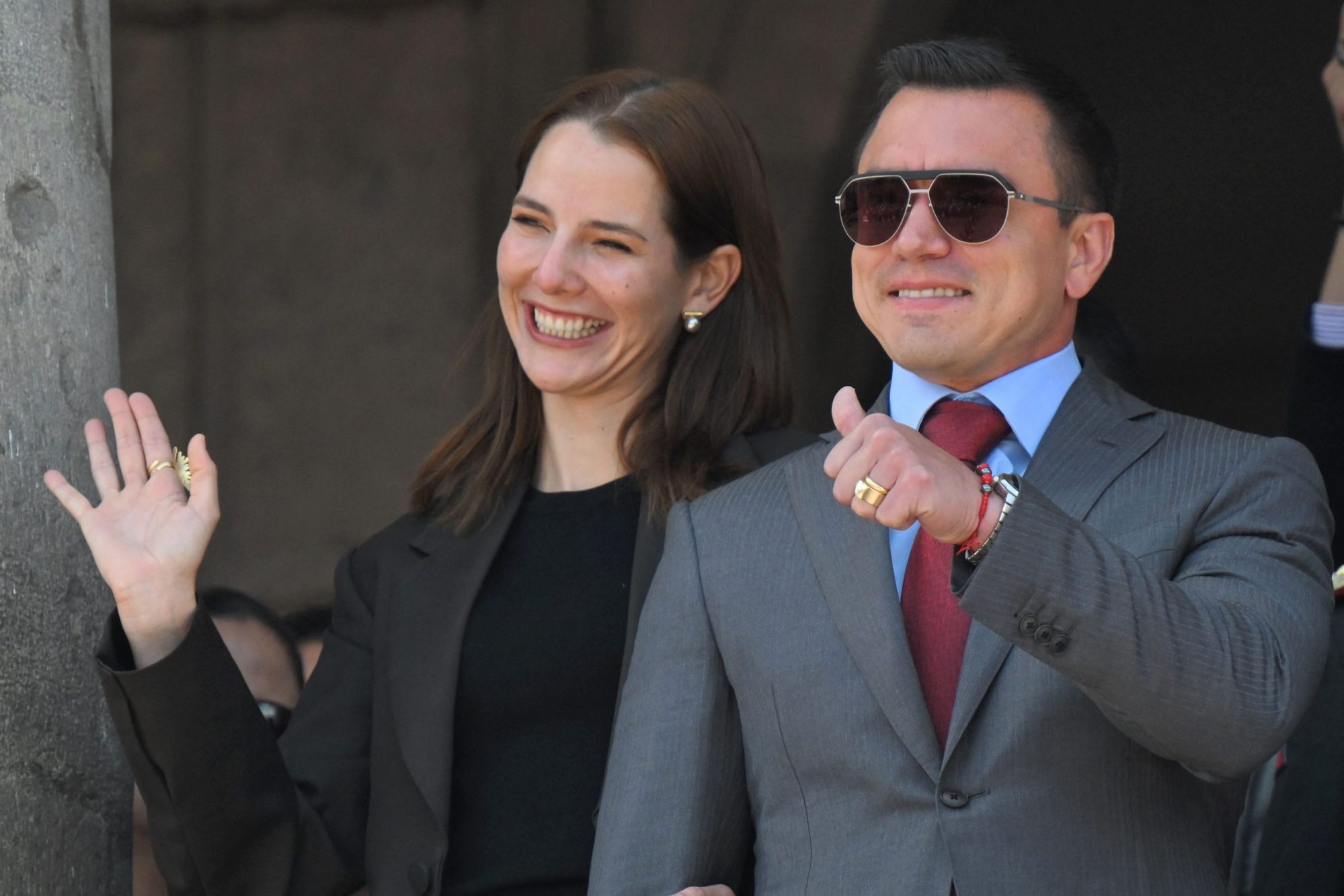 Ecuador's reelected President Daniel Noboa (R) thumbs up next to his wife, Lavinia Valbonesi, gesture from a balcony of the Carondelet Presidential Palace during the changing of the guard ceremony in Quito on April 15, 2025. Photo by RODRIGO BUENDIA/AFP via Getty Images