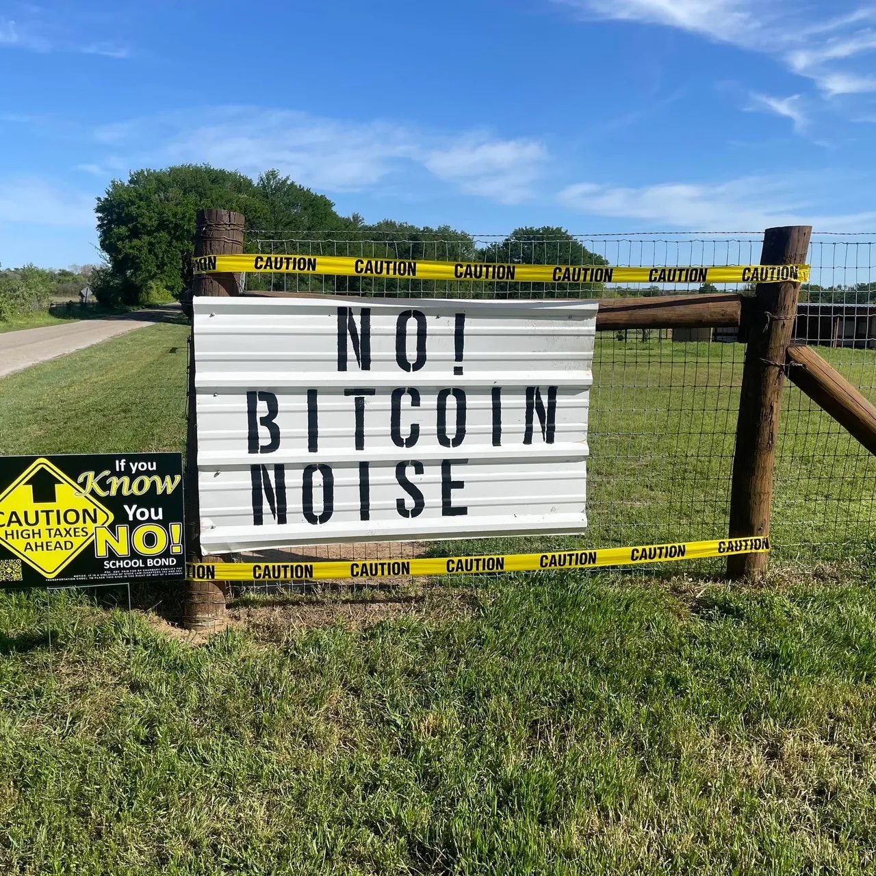 A sign on residential property in Granbury, TX, leans against a wooden fence. The sign says "No! Bitcoin Noise." Photo courtesy of Protect Hood County.