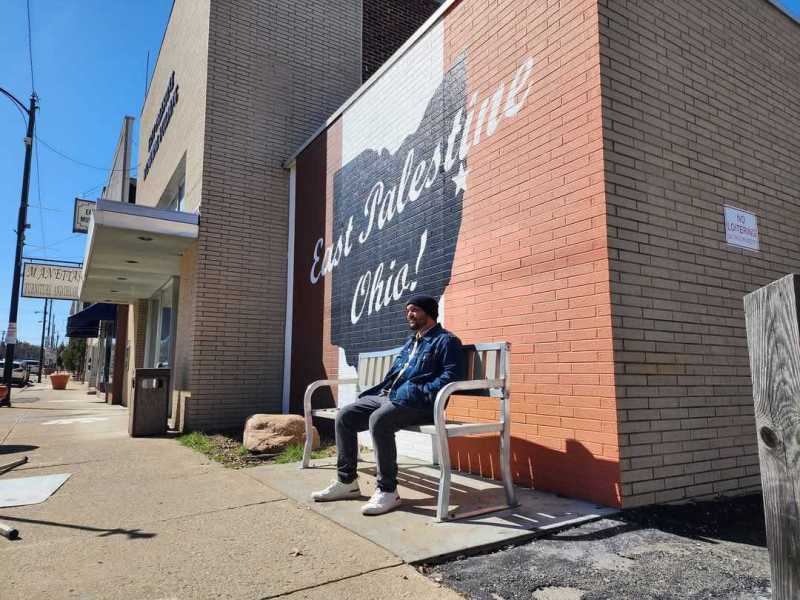TRNN Editor-in-Chief Maximillian Alvarez sits on a bench in downtown East Palestine, OH, on March 24, 2024. Photo by Mike Balonek.