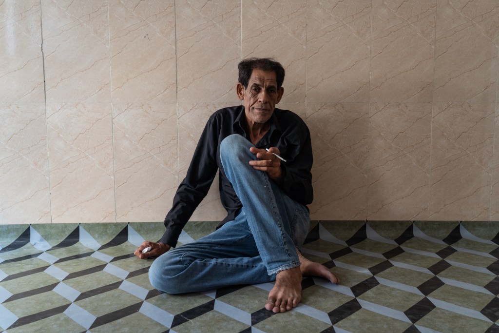 Majli sitting on the floor of the apartment he rents in Baghdad.