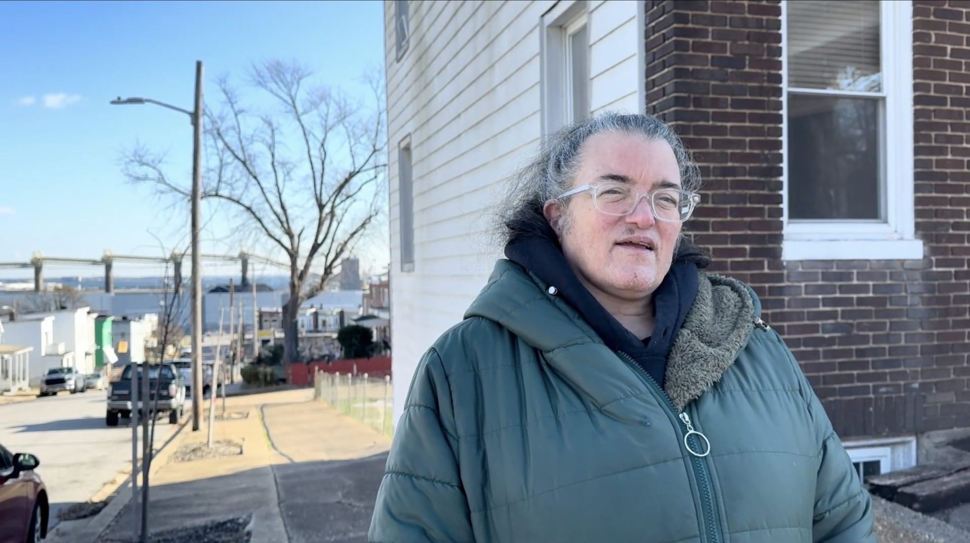 Angela "Angie" Shaneyfelt stands next to her home in Curtis Bay, South Baltimore, Maryland, with the CSX Transportation coal export terminal—which operates about 1,000 feet away from her residence—visible in the background. Photo taken by Maximillian Alvarez on Dec. 12, 2024.